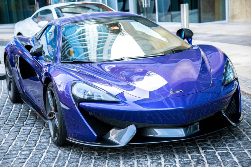 A shiny blue sports car parked on a cobbled street.