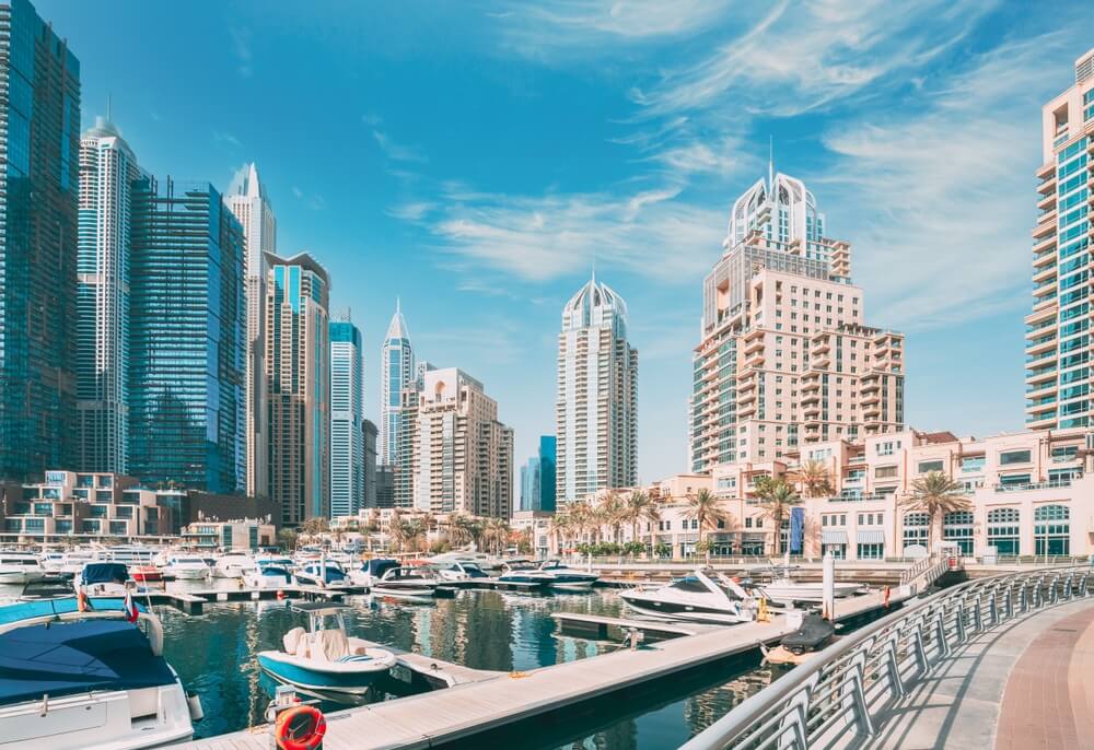 Dubai Marina with boats docked and towering skyscrapers in the background.