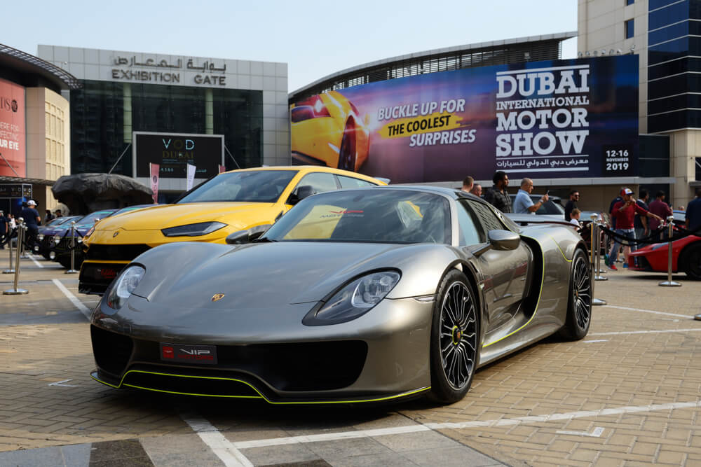 Porsche displayed at the Dubai International Motor Show with other luxury cars.