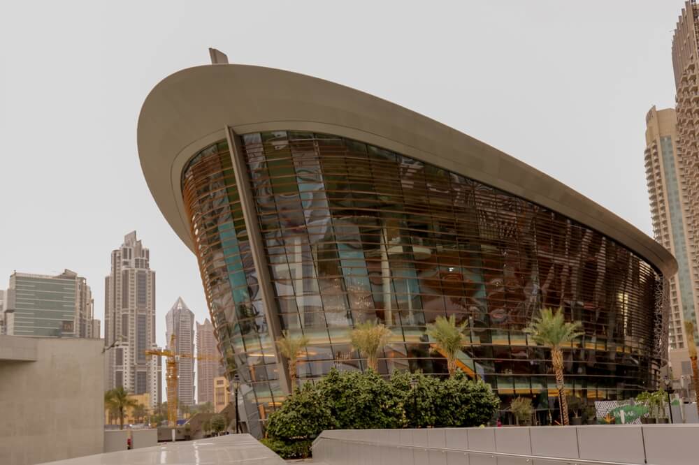 Exterior view of the Dubai Opera building with surrounding skyscrapers.