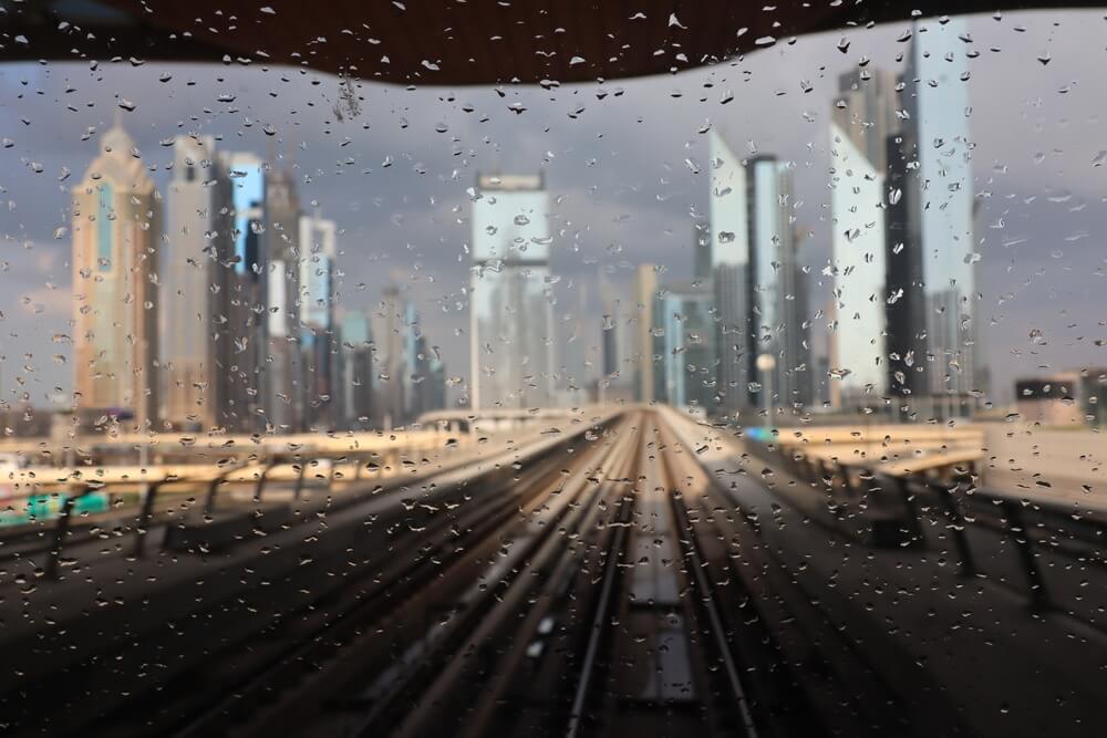 Dubai skyline viewed through a rainy window with water droplets.