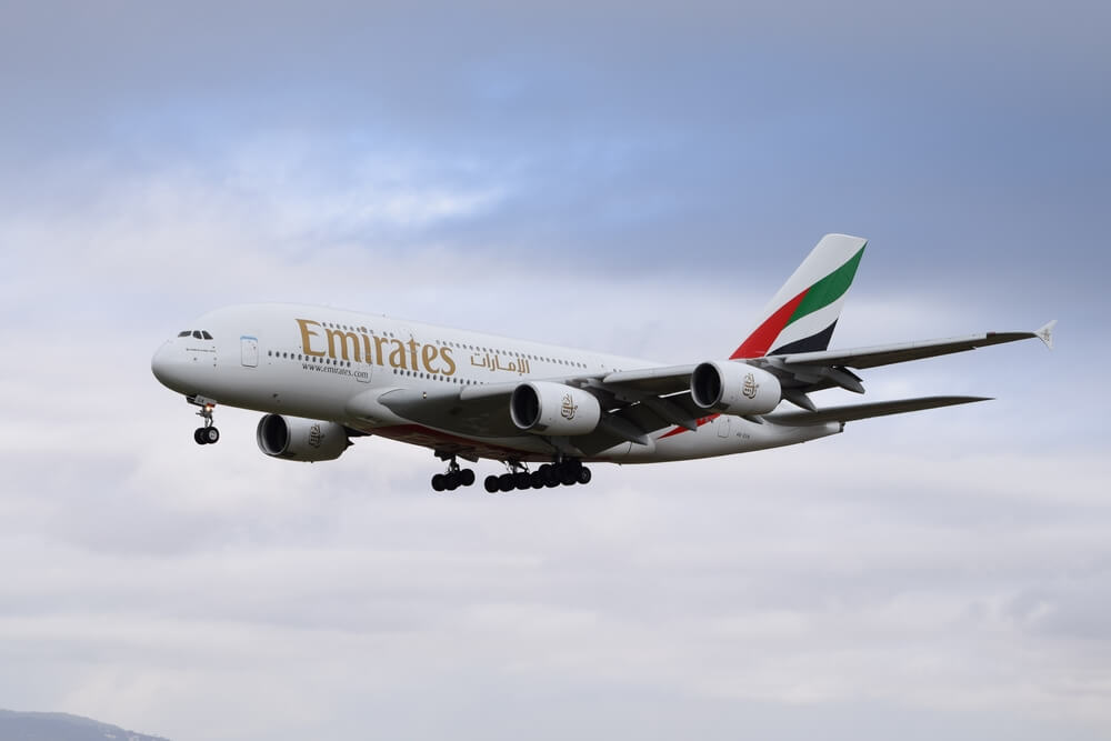 Emirates Airbus A380 airplane in flight with a cloudy sky.