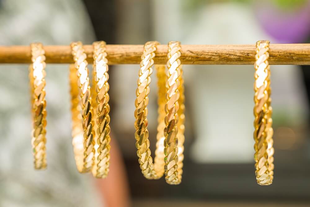 Gold braided bracelets displayed on a rack.