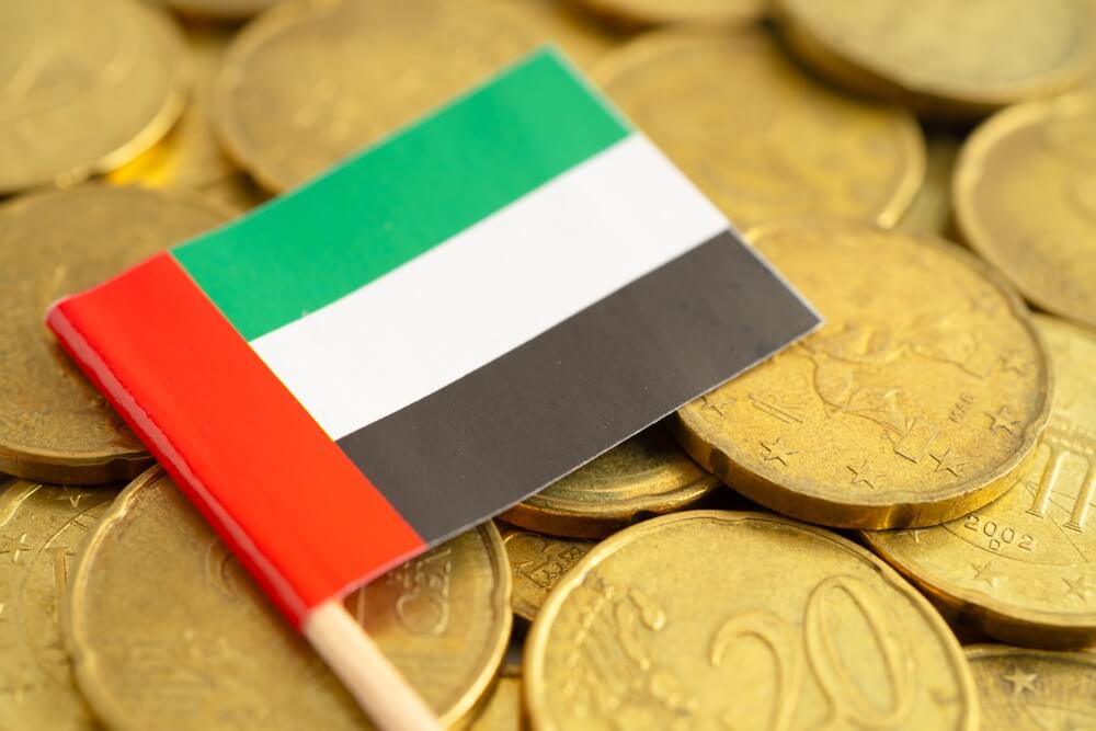 Small UAE flag on a stack of gold coins symbolizing wealth and patriotism.