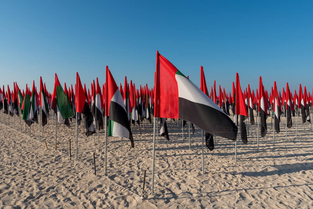 United Arab Emirates flags displayed on a sandy beach.